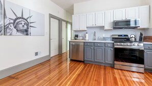 Una cucina moderna con mobili bianchi, elettrodomestici in acciaio inossidabile e pavimento in legno.