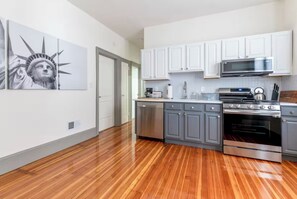 A modern kitchen with white cabinets, stainless steel appliances, and a wooden floor. - 10 min to Times Square - Luxury & Space 2Bd/1Ba (Weehawken Township)