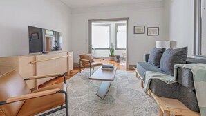 Un soggiorno moderno con un divano, un tavolino da caffè e una TV su un mobile in legno.