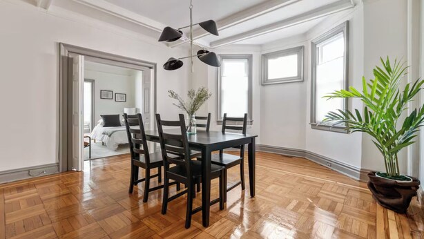 Un'ampia sala da pranzo con un tavolo e sedie in legno, una pianta in vaso e un lampadario moderno.