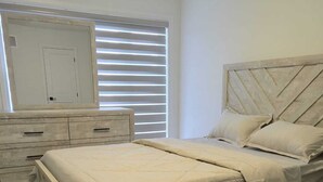 Un dormitorio con cama, cómoda y ventana con persianas.