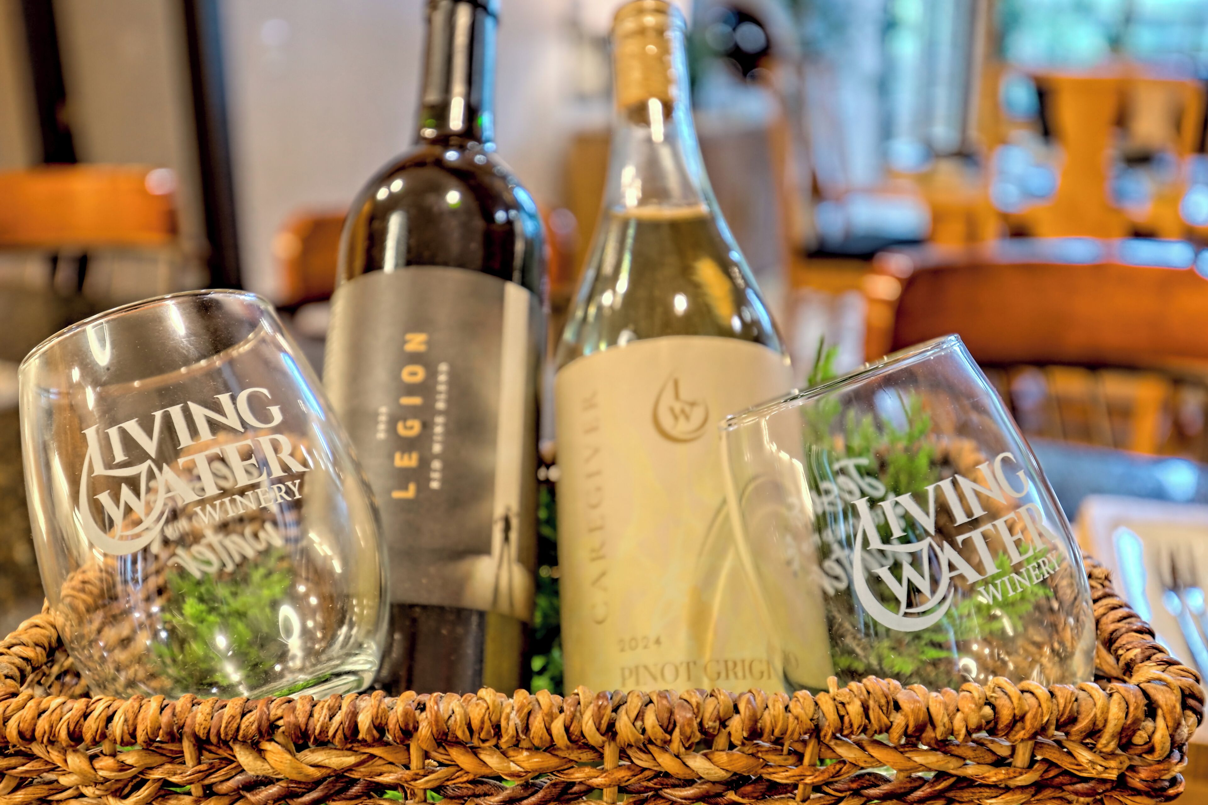 Una cesta de mimbre con botellas de vino y copas, con la etiqueta 'Living Water Winery'.