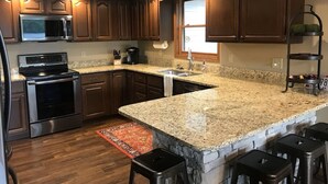 Eine moderne Küche mit Granit Arbeitsplatten, Edelstahlgeräten und Holzschränken.