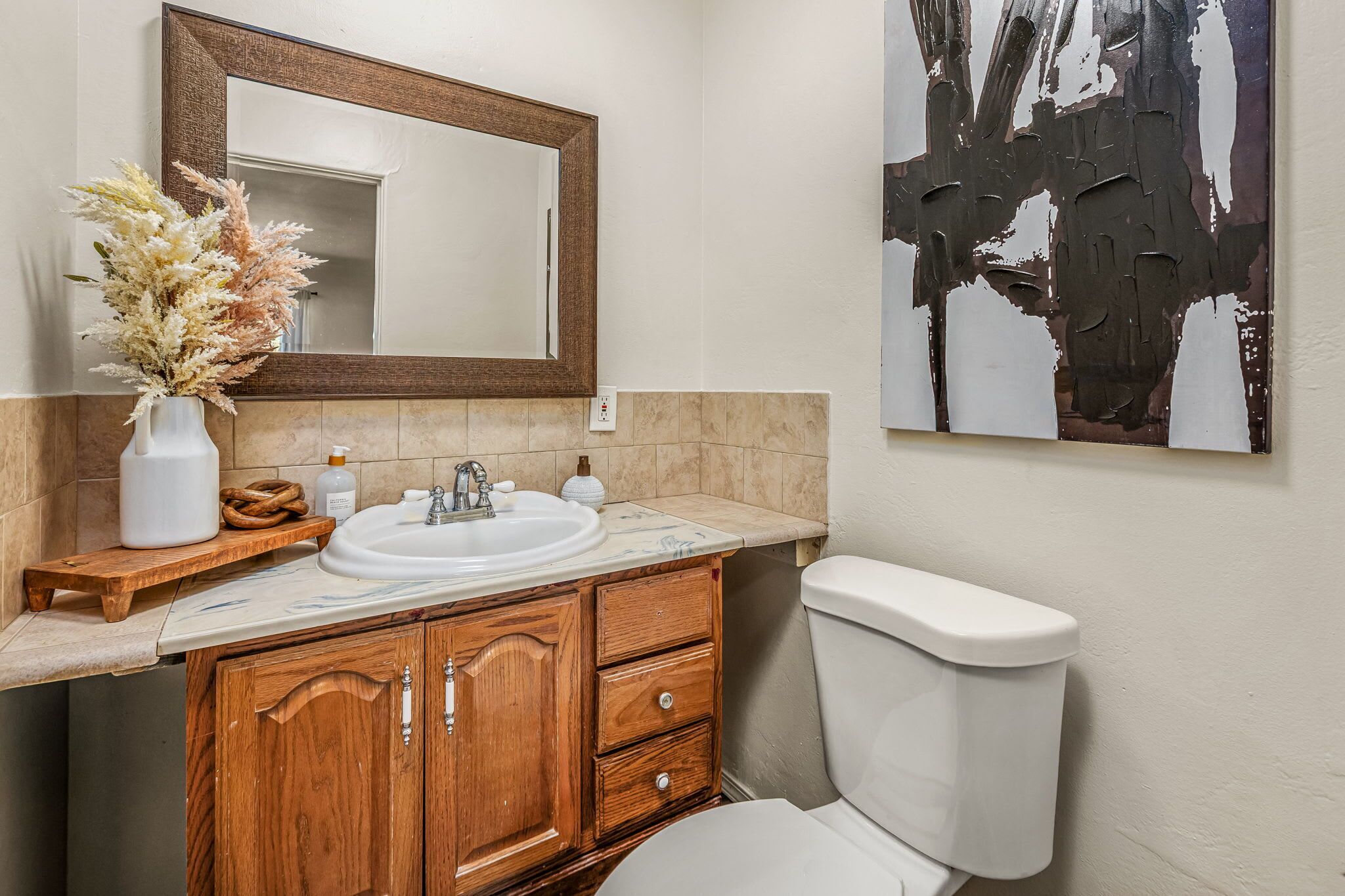 Un baño con tocador de madera, lavabo blanco y un espejo grande.