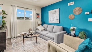 Ein Wohnzimmer mit grauem Sofa, einem beigen Sessel, einem Couchtisch und einer blauen Akzentwand.