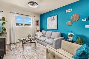 Ein Wohnzimmer mit grauem Sofa, einem beigen Sessel, einem Couchtisch und einer blauen Akzentwand.