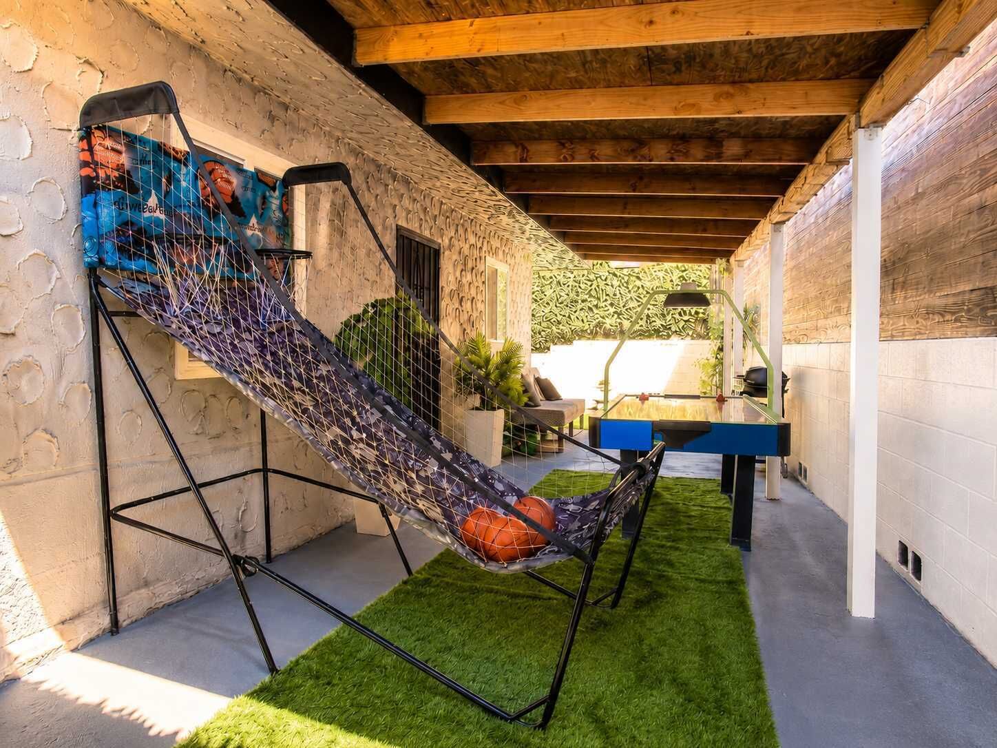 Un'amaca con un pallone da basket su un pavimento di erba sintetica verde, un soffitto in legno e un muro in pietra.