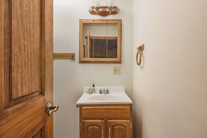 A bathroom with a wooden vanity, a mirror, and a sink. - Denali Outpost Apartment for Large Groups (Trapper Creek)