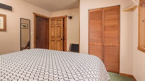 Una camera da letto con una coperta a motivi, un armadio in legno e uno specchio appeso al muro.
