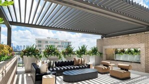 Une terrasse sur le toit dotée d’un espace salon abrité, de plantes en pot et offrant une vue sur le paysage urbain.