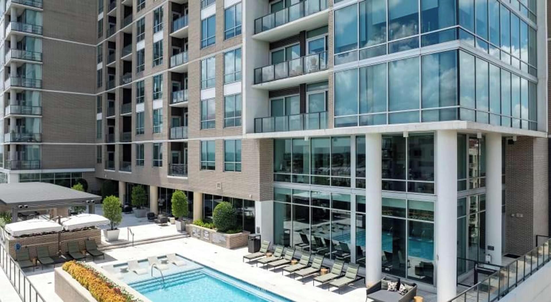 A multi-story hotel with a rooftop pool area, outdoor seating, and a glass facade.