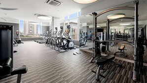 Ein modernes Fitnessstudio mit Laufbändern, Krafttrainingsgeräten und einem großen Spiegel.