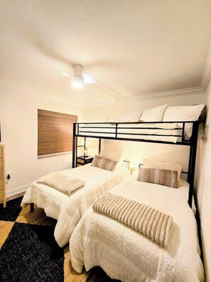 A bedroom with two bunk beds, a bedside table, a lamp, and a window with blinds. - St. Johns Riverside Retreat, fish, boat, relax. Long stays welcome. (Astor)