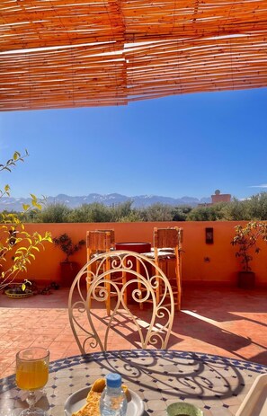 A terrace with a table, chairs, and a view of mountains. - Domaine JJ – Guesthouse with pool, garden & Atlas view near Marrakech (Marrakech)