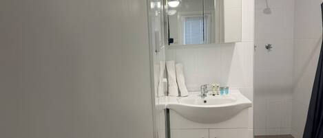 A modern bathroom with a white sink, mirror, and cabinets.