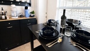 Una cocina moderna con armarios negros, una encimera de madera y una mesa de comedor dispuesta con platos, vasos y cubiertos negros.