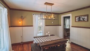 A dining area with a wooden table, benches, a chandelier, and a view of the outdoors. - Gangsters Paradise @ Renegade Hideaways (Niles)
