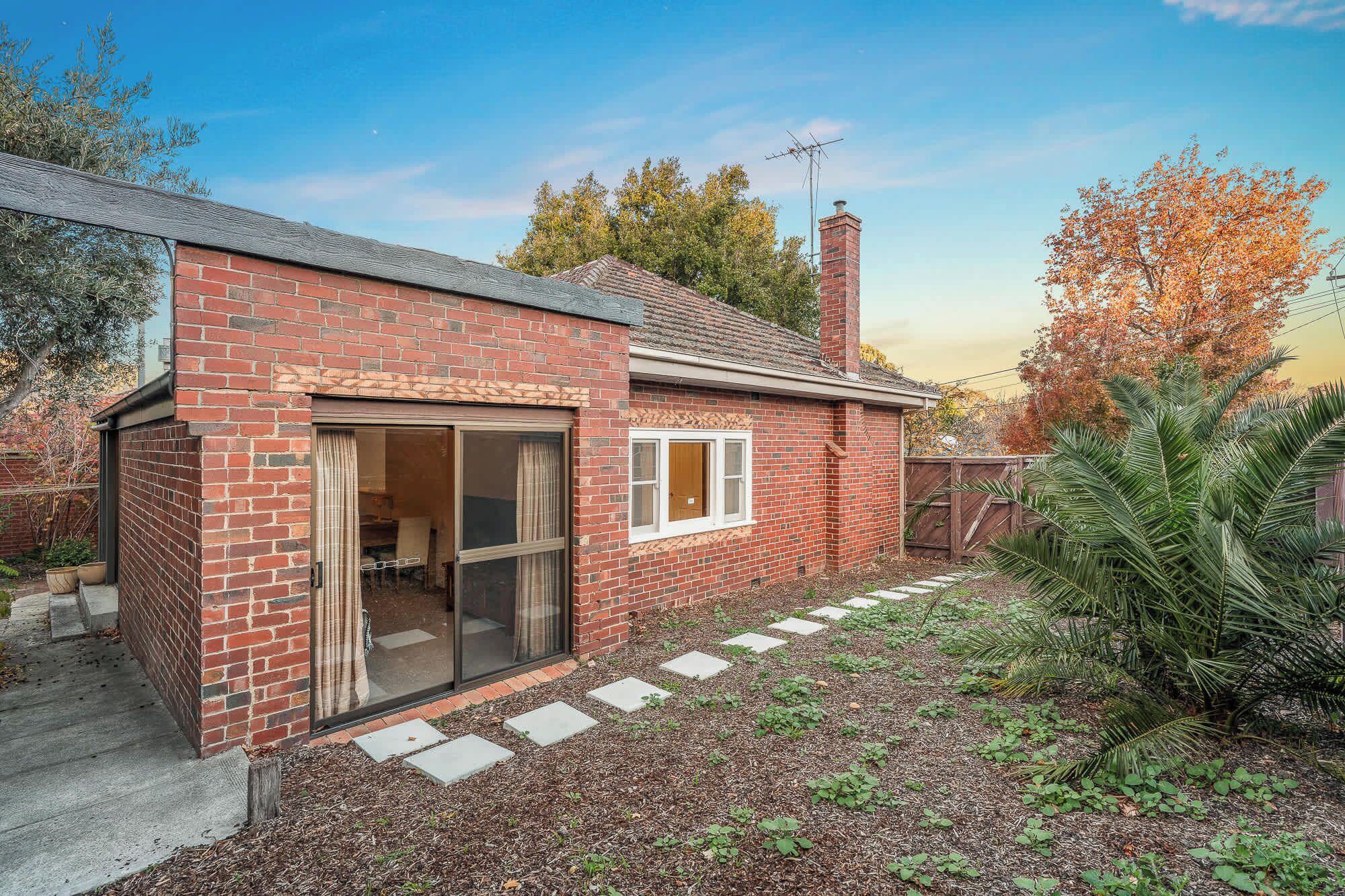 A brick house with a sliding glass door, a small window, and a chimney.