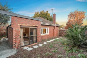 A brick house with a sliding glass door, a small window, and a chimney. - Charming Cozy Home Near Local Shops & Chadstone SC (Camberwell)