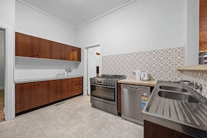 A kitchen with wooden cabinets, a stove, oven, and a dishwasher. - Charming Cozy Home Near Local Shops & Chadstone SC (Camberwell)