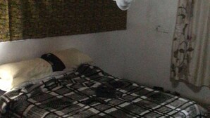 Ein Einzelbett mit karierter Bettdecke, einem weißen Kissen und einem Baldachin mit Spitzenbesatz.