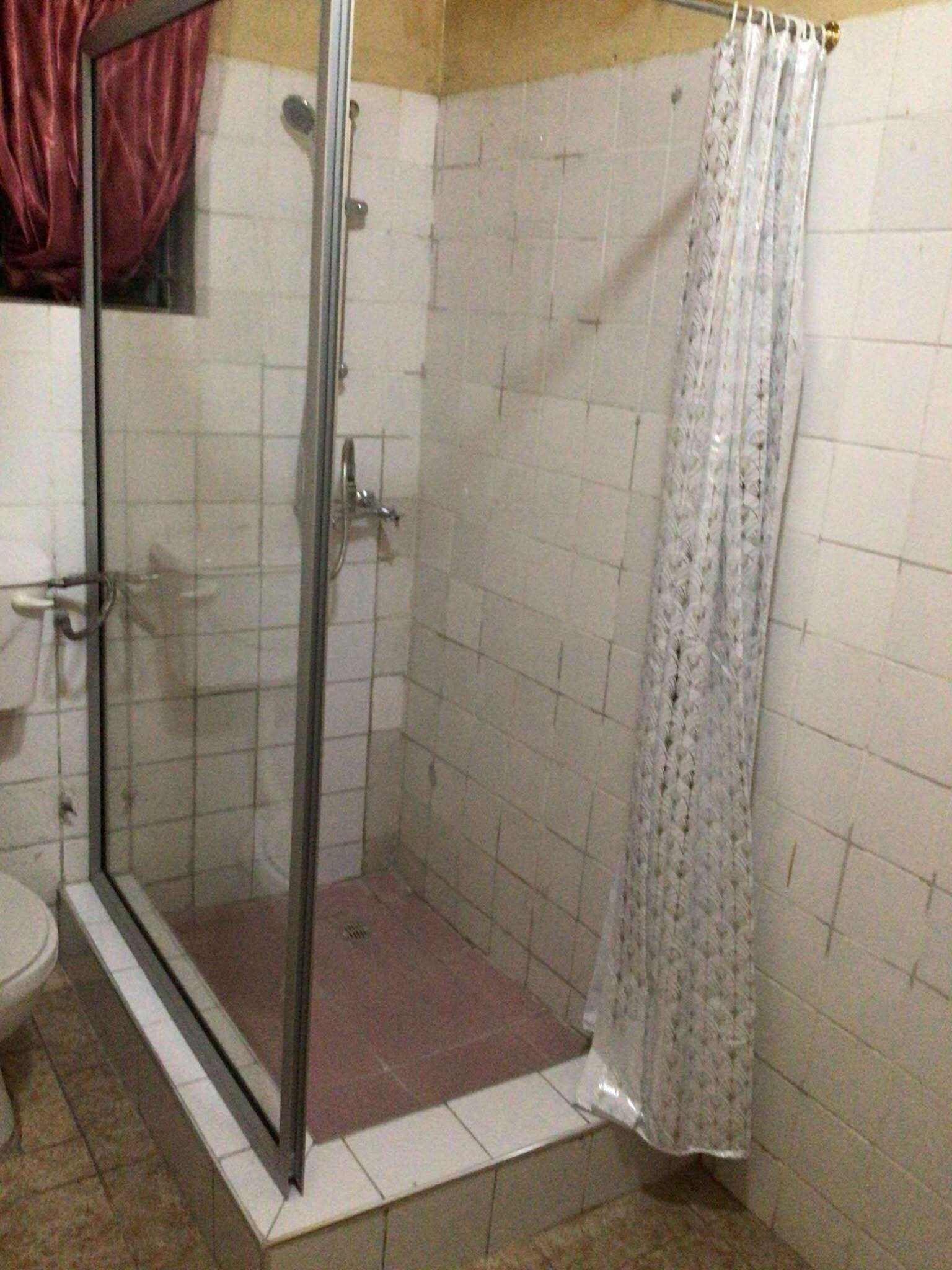 A shower with a glass door, a toilet, and a tiled floor.