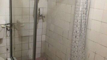 A shower with a glass door, a toilet, and a tiled floor.