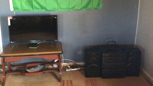 Ein Zimmer mit einer Flagge, einer Uhr, einem Tisch mit einem Laptop und einem Lautsprecher.