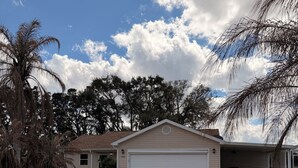 A residential house with a garage, paved driveway, and landscaped yard. - 2-bedroom house in the villages with golf course view and included golf cart! (Lady Lake)