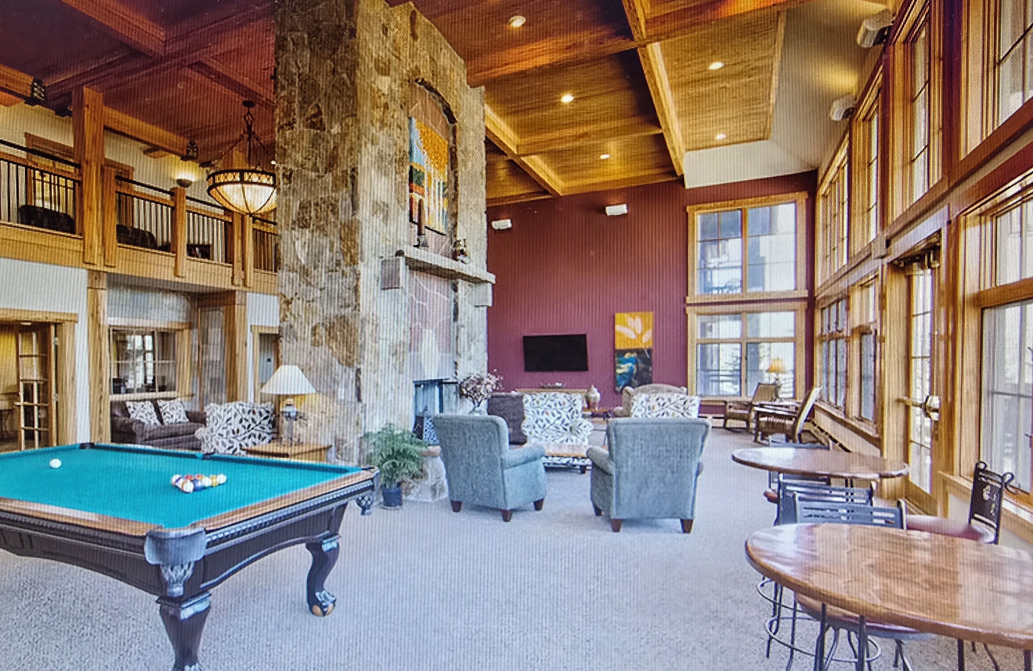 Un hall d’entrée spacieux avec une table de billard, des sièges confortables et de grandes fenêtres.