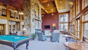 Un hall d’entrée spacieux avec une table de billard, des sièges confortables et de grandes fenêtres.