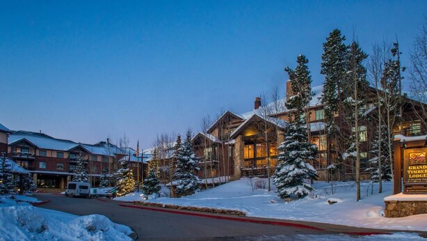Un chalet doté d’une façade en pierre, de grandes fenêtres et surplombant un paysage enneigé.
