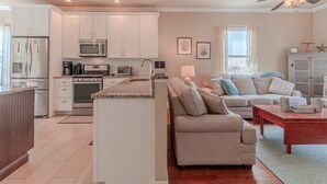 Una cocina moderna con armarios blancos, una isla central y un área de comedor con un sofá y una mesa de centro.