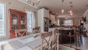 Una cocina amplia con zona de comedor, armarios de madera e iluminación colgante.