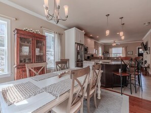 A spacious kitchen with a dining area, wooden cabinets, and pendant lighting. - Steps to the Beach. 4 Bedrooms. Occupancy 10 (Town Bank)