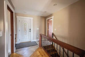 A hallway with a wooden staircase, a white door with a stained glass window, and beige walls. - The Lookout at Buckleberry View, EV Charging (Spring Mills)