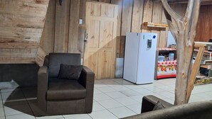 Un interior de madera con un sofá, un refrigerador y una mesa con mantel floreado.