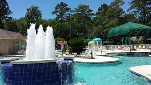 A swimming pool with a water fountain, lounge chairs, and umbrellas. - Island Links - 3BR/2BA - Great Pool Complex! (Hilton Head Island)