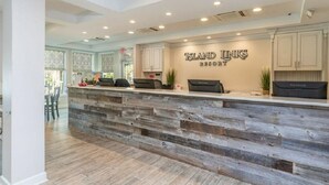 A reception desk with a rustic wooden design, a sign reading "Island Links Resort," and a view of the adjacent dining area. - Island Links - 3BR/2BA - Great Pool Complex! (Hilton Head Island)