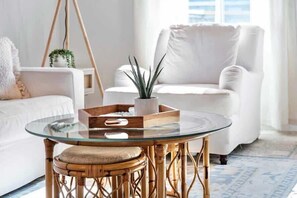 A modern living room with a glass-top coffee table, a wicker chair, and a white sofa. - Bayfront Paradise, Pool, Boat Slip, Townhome (Ocean City)