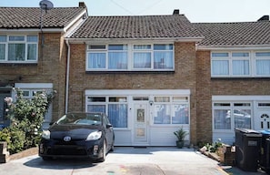 A two-story house with a car parked in the driveway and a satellite dish on the roof.