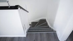 A staircase with a black handrail and white walls. - Abe’s Home (London)