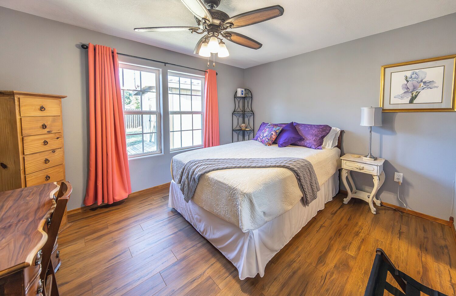 A bedroom with a bed, wooden dresser, desk, and chair.