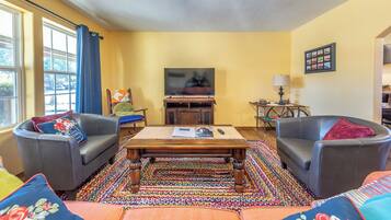 Una sala de estar con dos sillones de cuero, una mesa de centro de madera y una alfombra colorida.