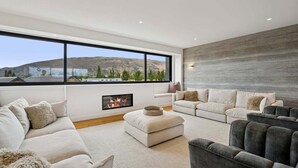 A modern living room with a fireplace, large windows, and a view of the mountains. - Rubus Street Residence | Brand-New 4 Bedroom, 4 Bathroom Retreat in Wanaka (Wanaka)
