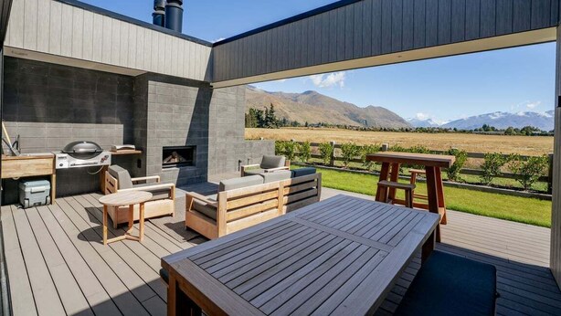 An outdoor deck with a barbecue, seating area, and a view of mountains. - Rubus Street Residence | Brand-New 4 Bedroom, 4 Bathroom Retreat in Wanaka (Wanaka)