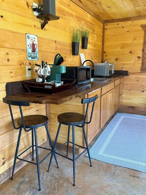 A wooden interior with a bar area, stools, a microwave, a toaster, and a coffee machine. - Cozy and Comfortable Cabin in Spencer. Fall Creek Falls nearby
Book Now for Fall (Spencer)