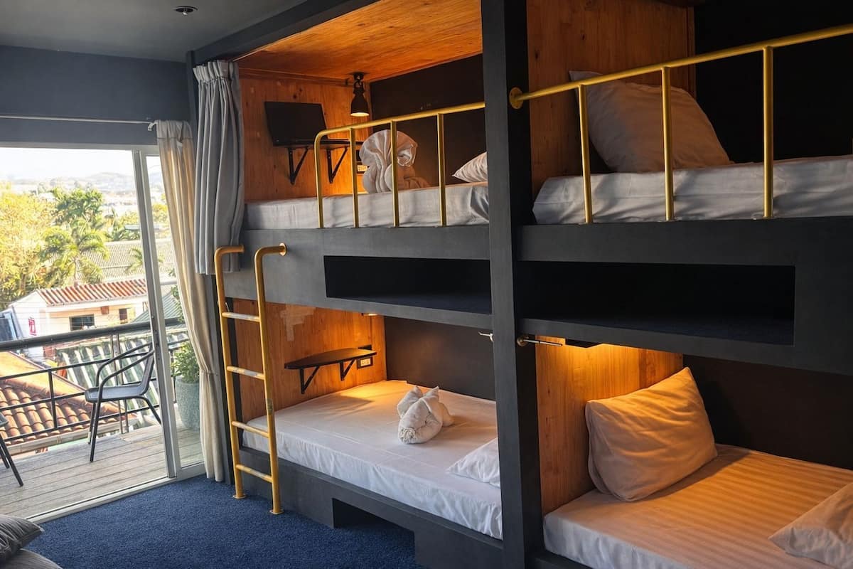 A bunk bed room with a view of the outdoors, a small table, and a chair.
