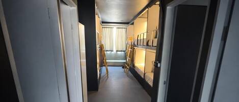 A narrow hallway with bunk beds, a ladder, and a door at the end.