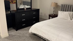 A bedroom with a bed, a dresser, a mirror, a lamp, and a painting on the wall.